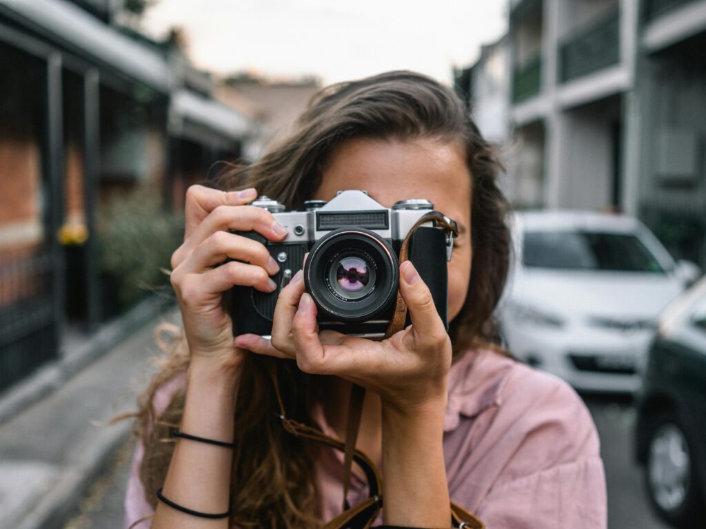 A woman captures a street scene with a classic camera in Surry Hills, Australia.