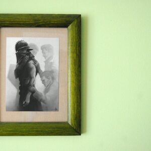 Green wooden frame holding a grayscale art print on a soft green wall.