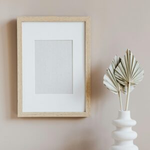 Elegant minimalist interior with a wooden frame and sculptural vase on a marble surface.