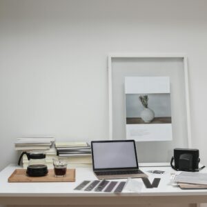 Photographer working desk with modern laptop and filmstrips scattered near film camera and glass of coffee decorated with framed picture